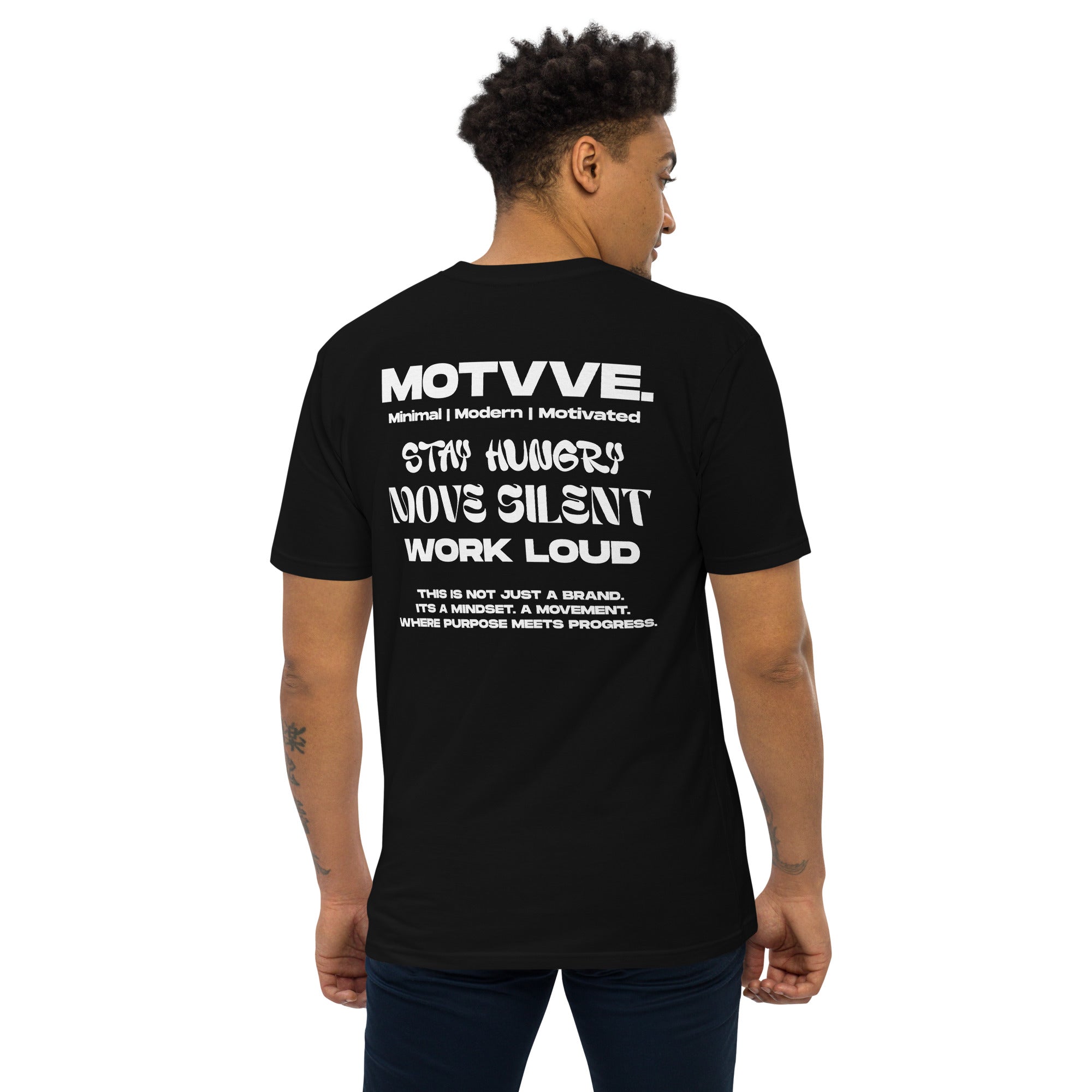 Person wearing a black t-shirt with white text on the back saying 'MOTVVE', standing against a white background